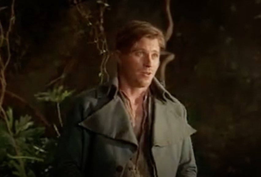 Actor Garrett Hedlund wears a green coat and stands in a forest