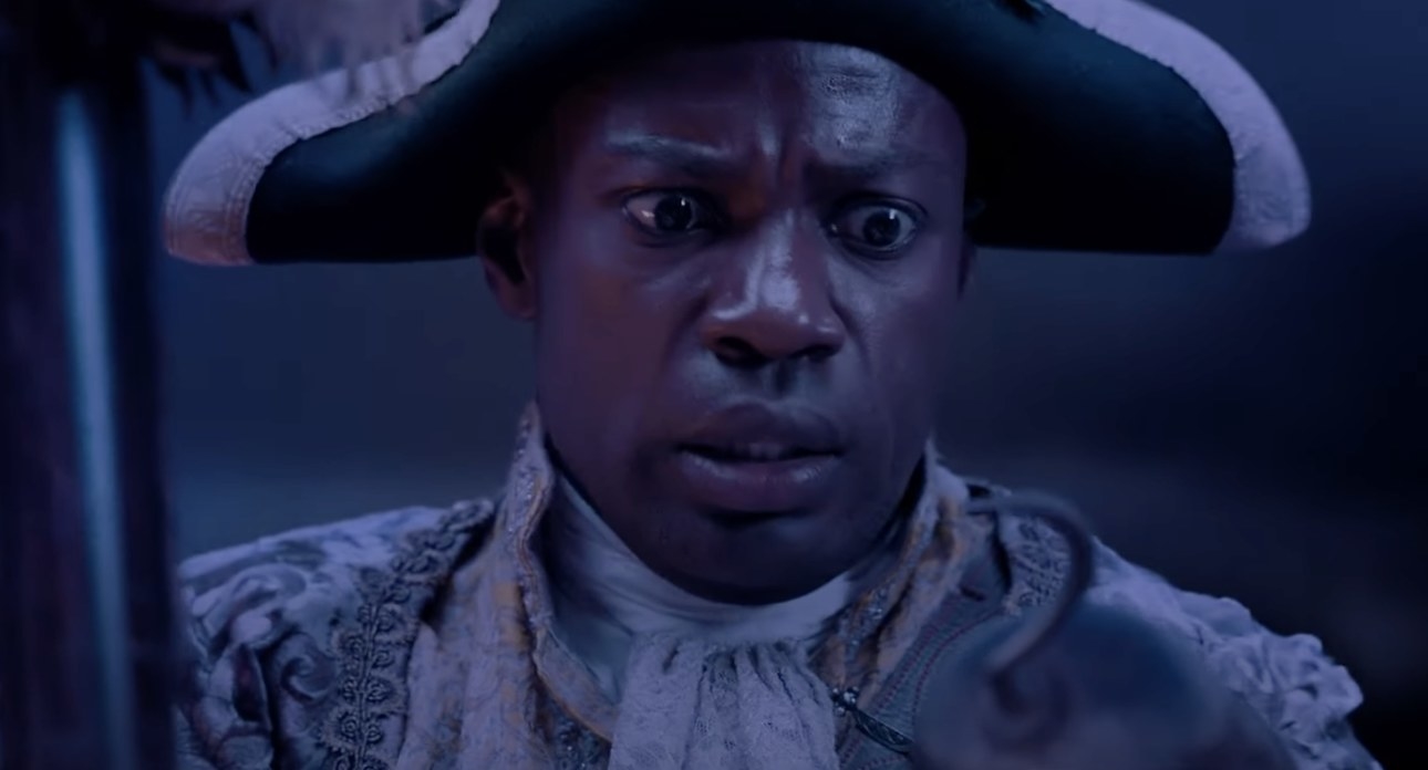 a man in a pirate hat looks at a hook with a worried look