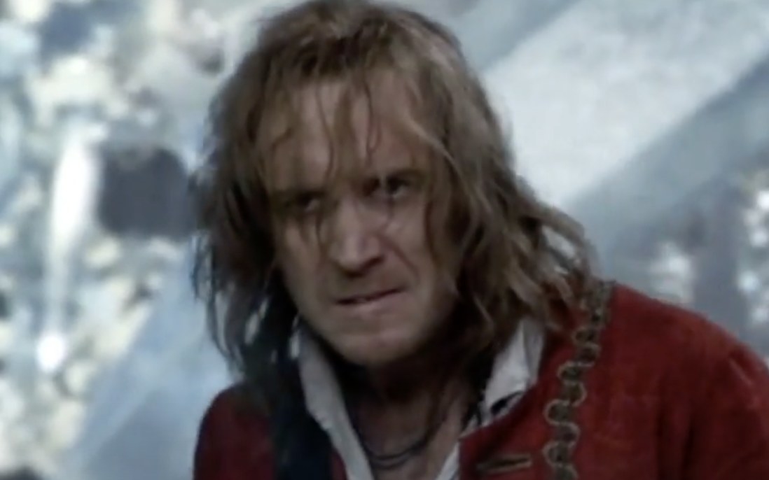 a man with long hair and a red coat looks angry