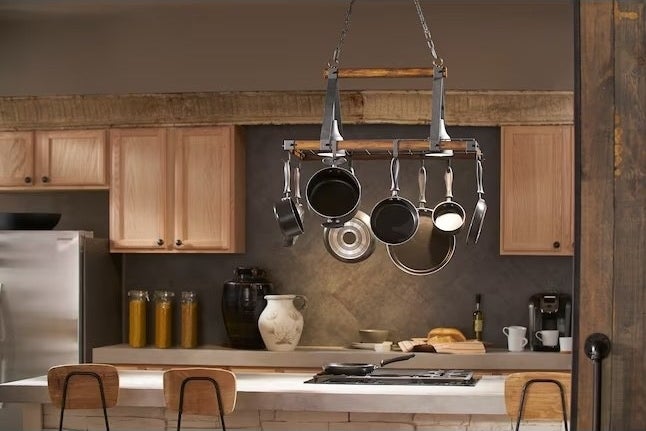 a pot rack holding eight pots and pans above a kitchen island