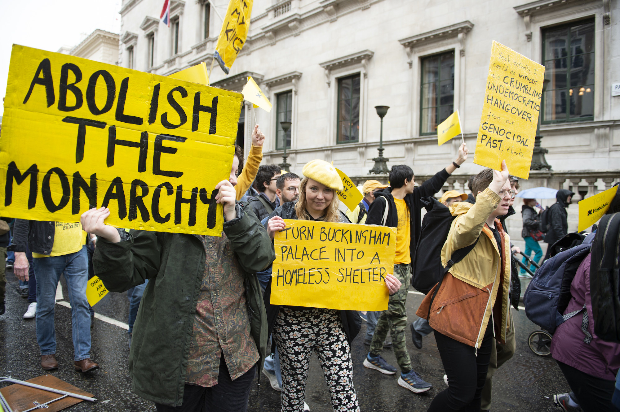 crowd with signs, abolish the monarchy, turn buckingham palace into a homeless shelter