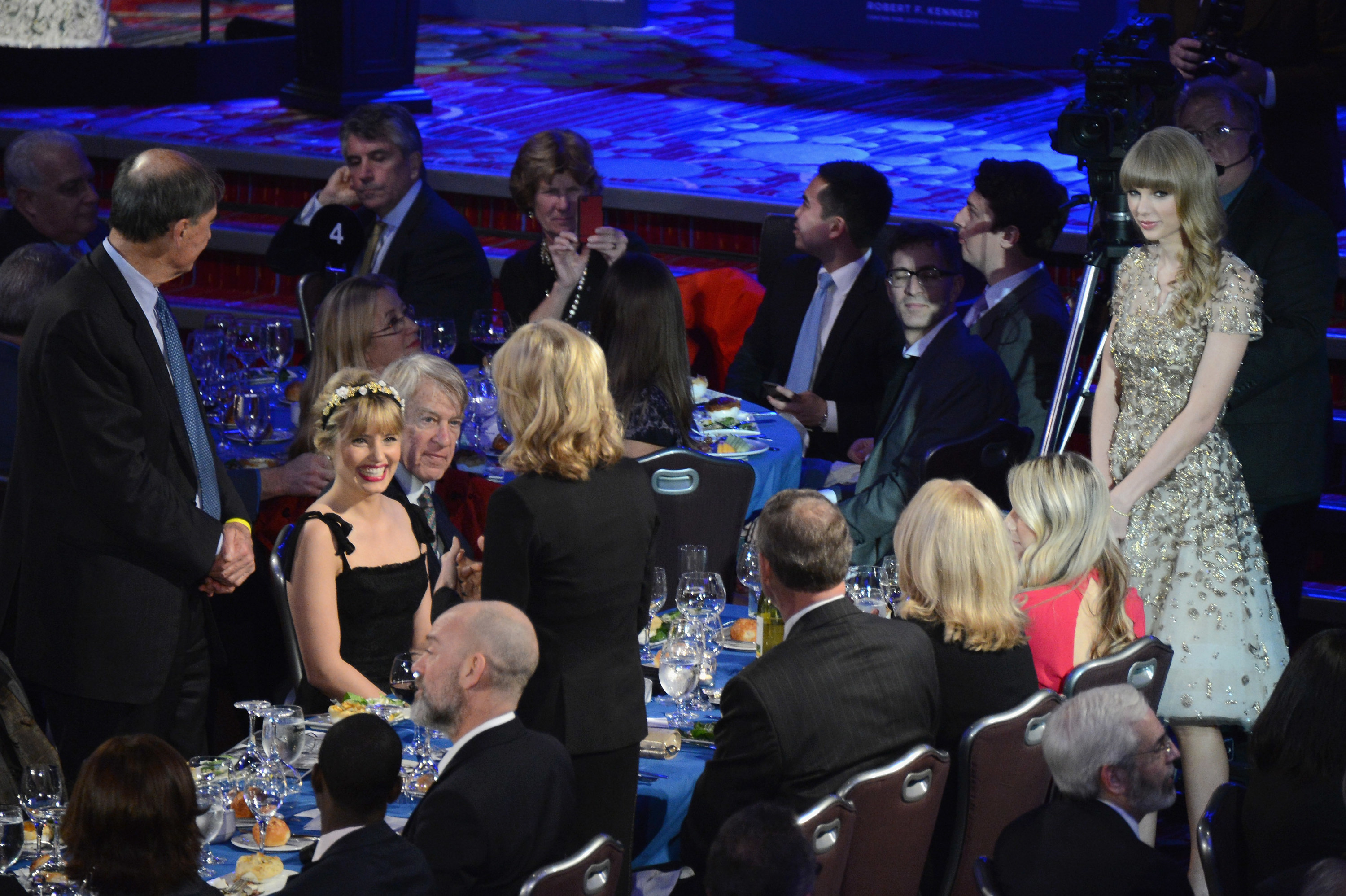 Taylor Swift standing at a table at a benefit
