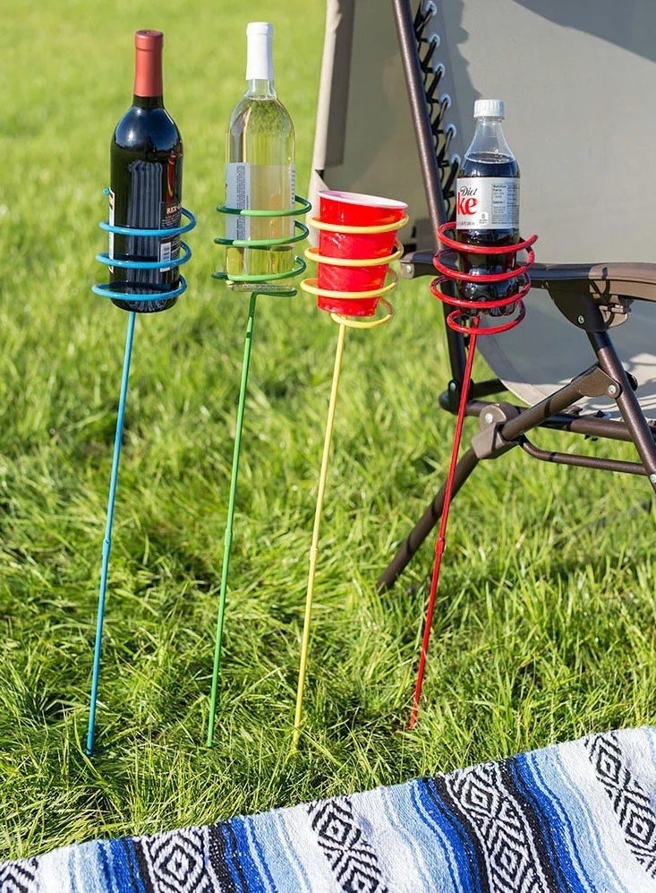 the set of four stakes planted in the grass, with each one holding a different drink