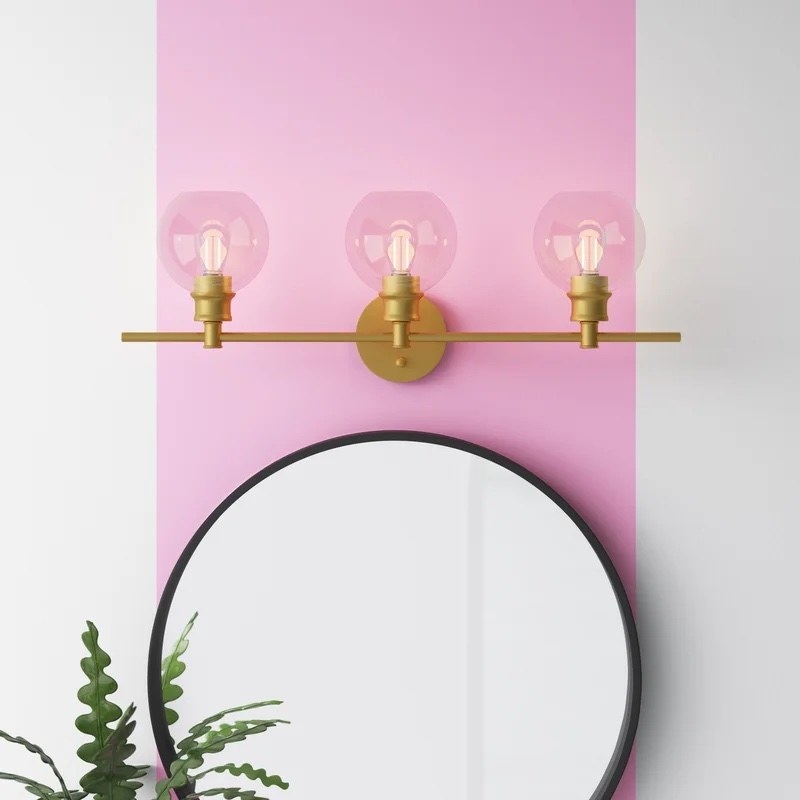 the brass light fixture above a round mirror
