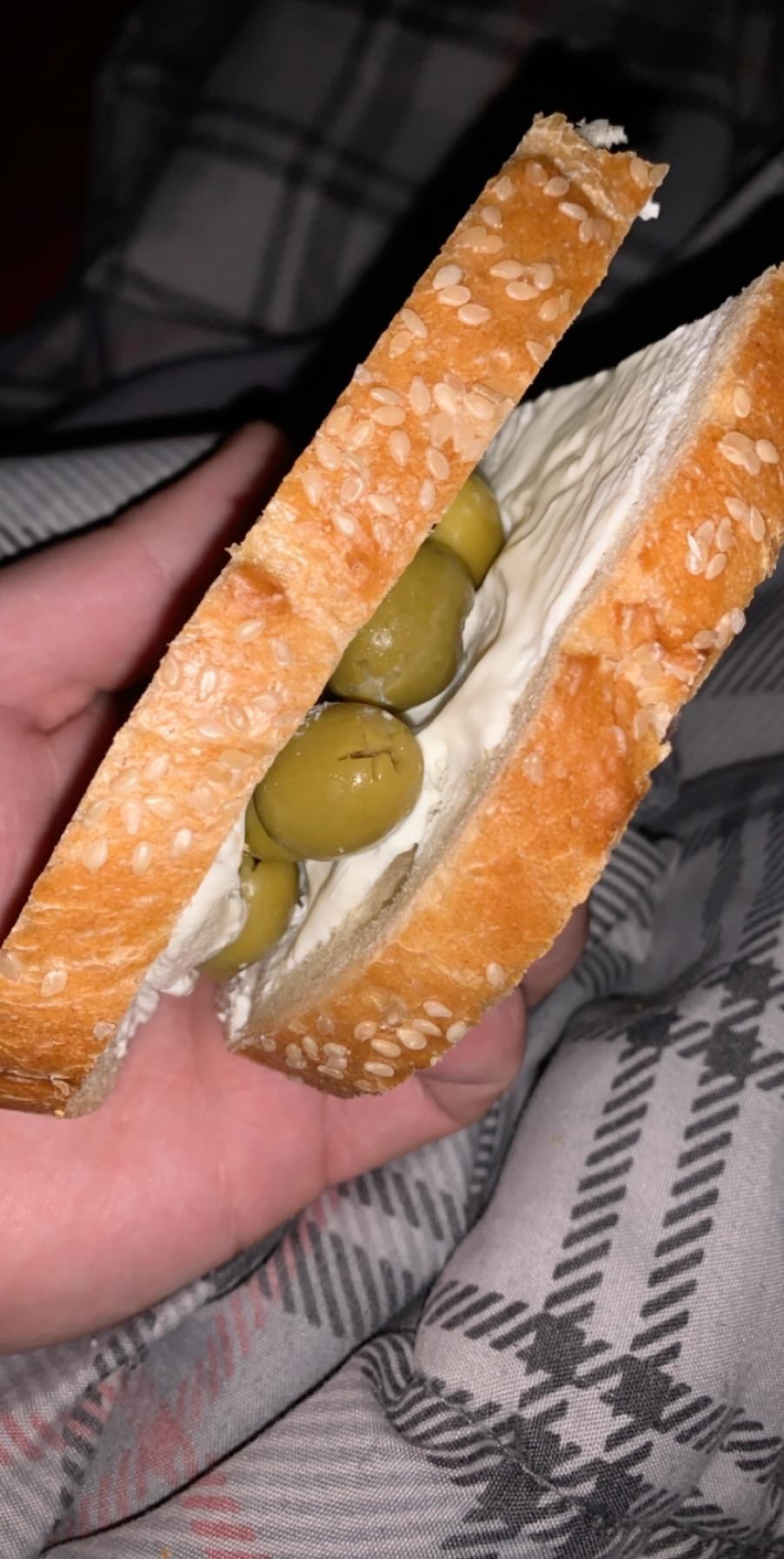 A cream cheese sandwich with green olives.