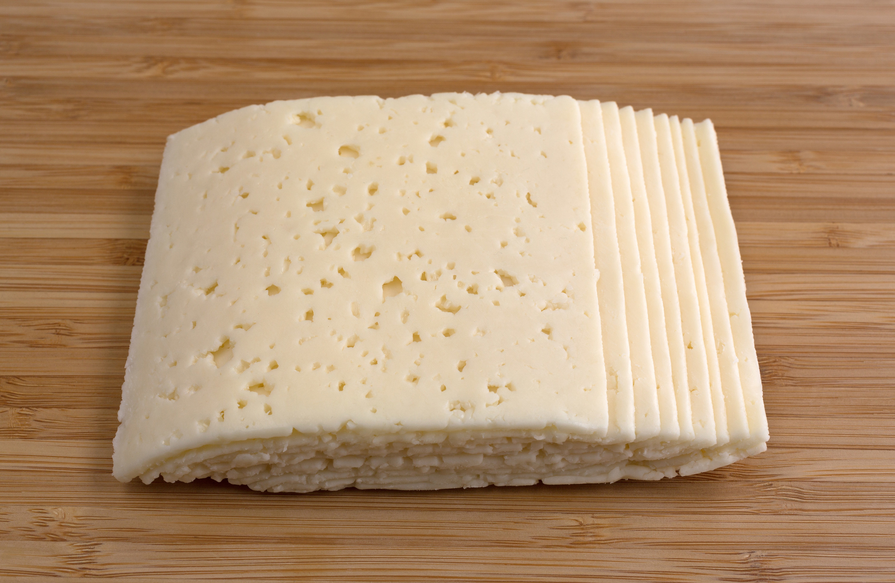 Slices of Havarti cheese on a cutting board.