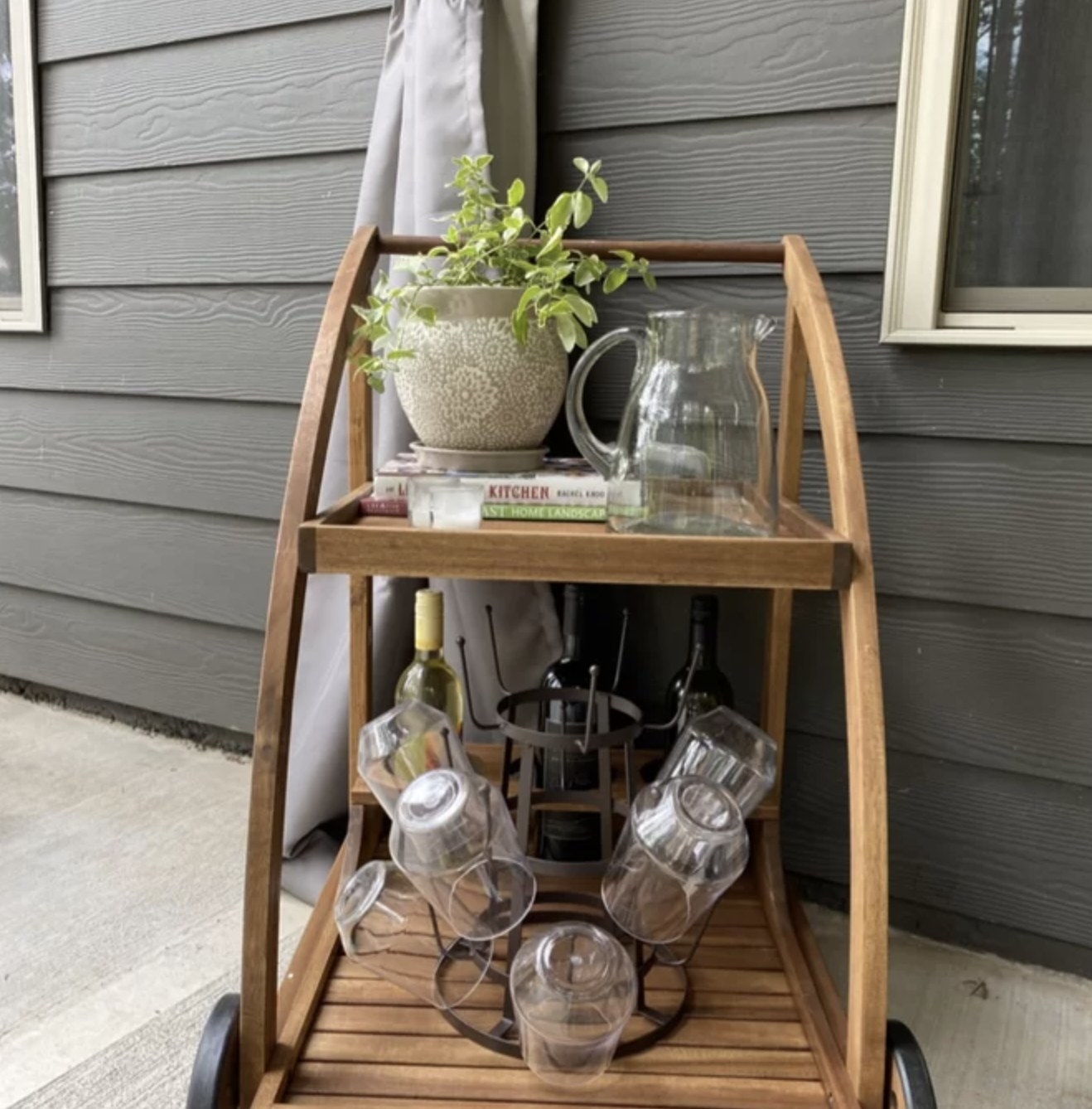 Reviewer's cart with glassware and wine on bottom level and plants, books, and pitcher on top shelf