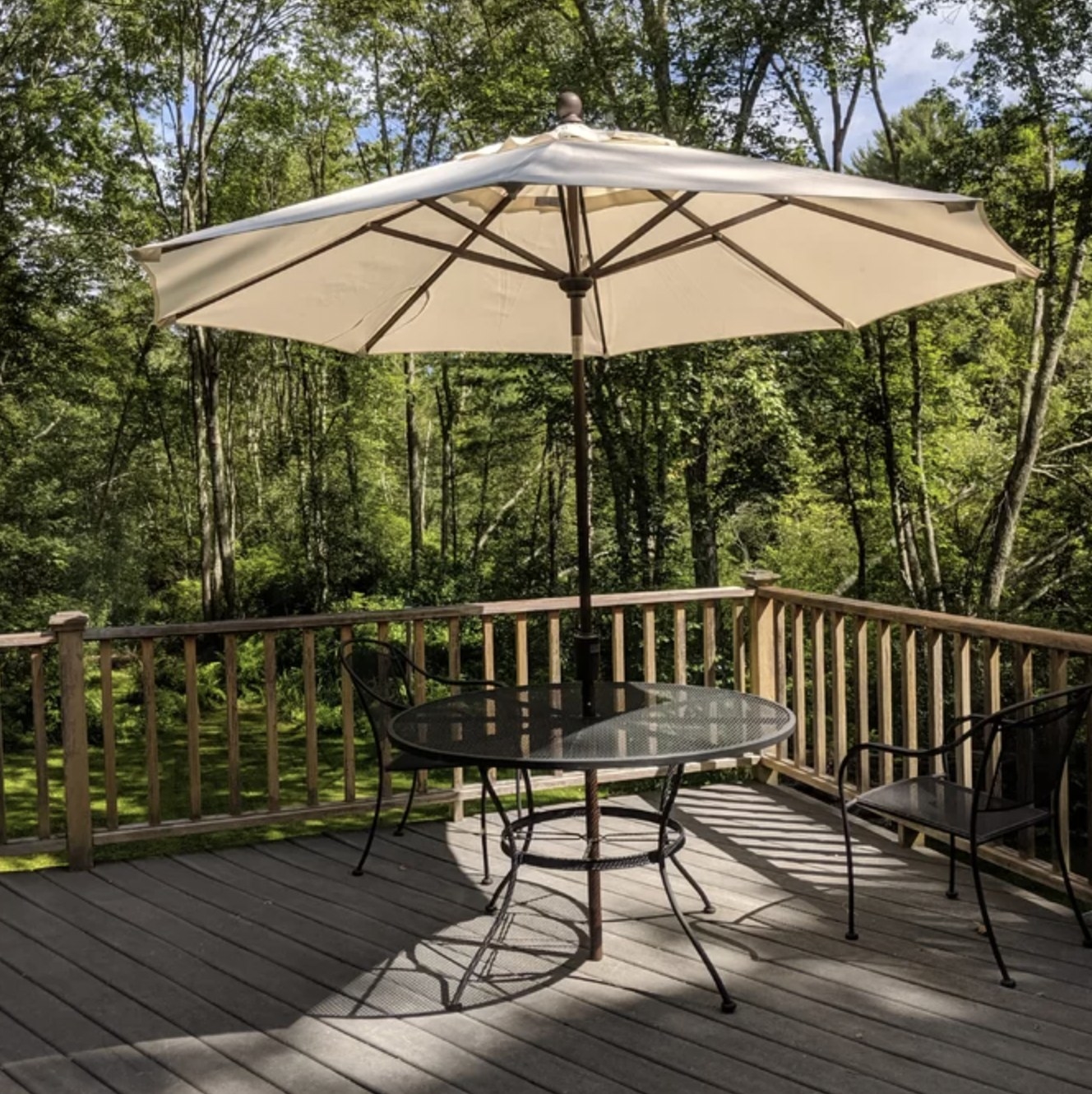Reviewer's beige umbrella open over table on patio