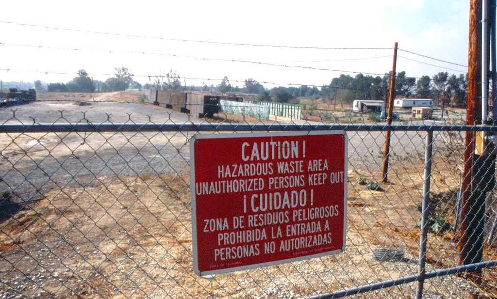 A caution hazardous waste sign in front of a site