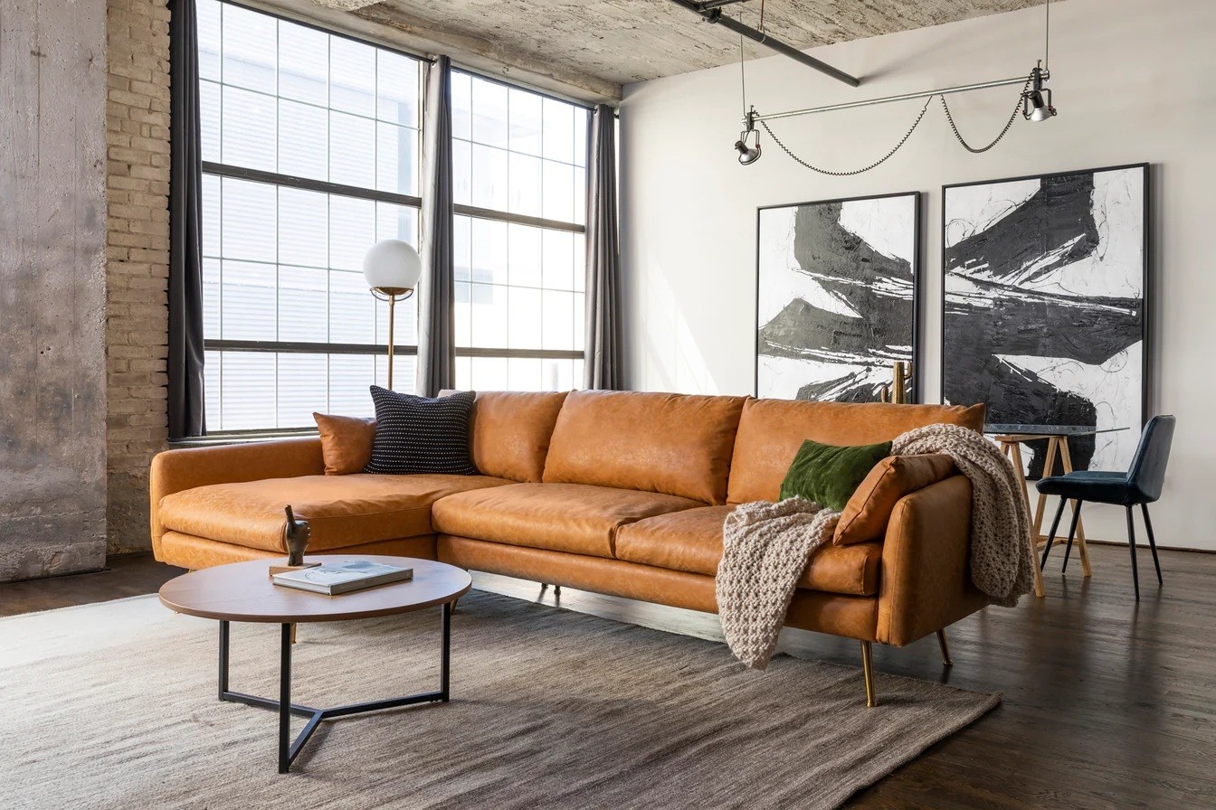 A tan faux leather sectional is shown in a living room