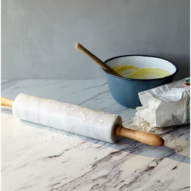 a marble countertop with a rolling pin and flour on it.