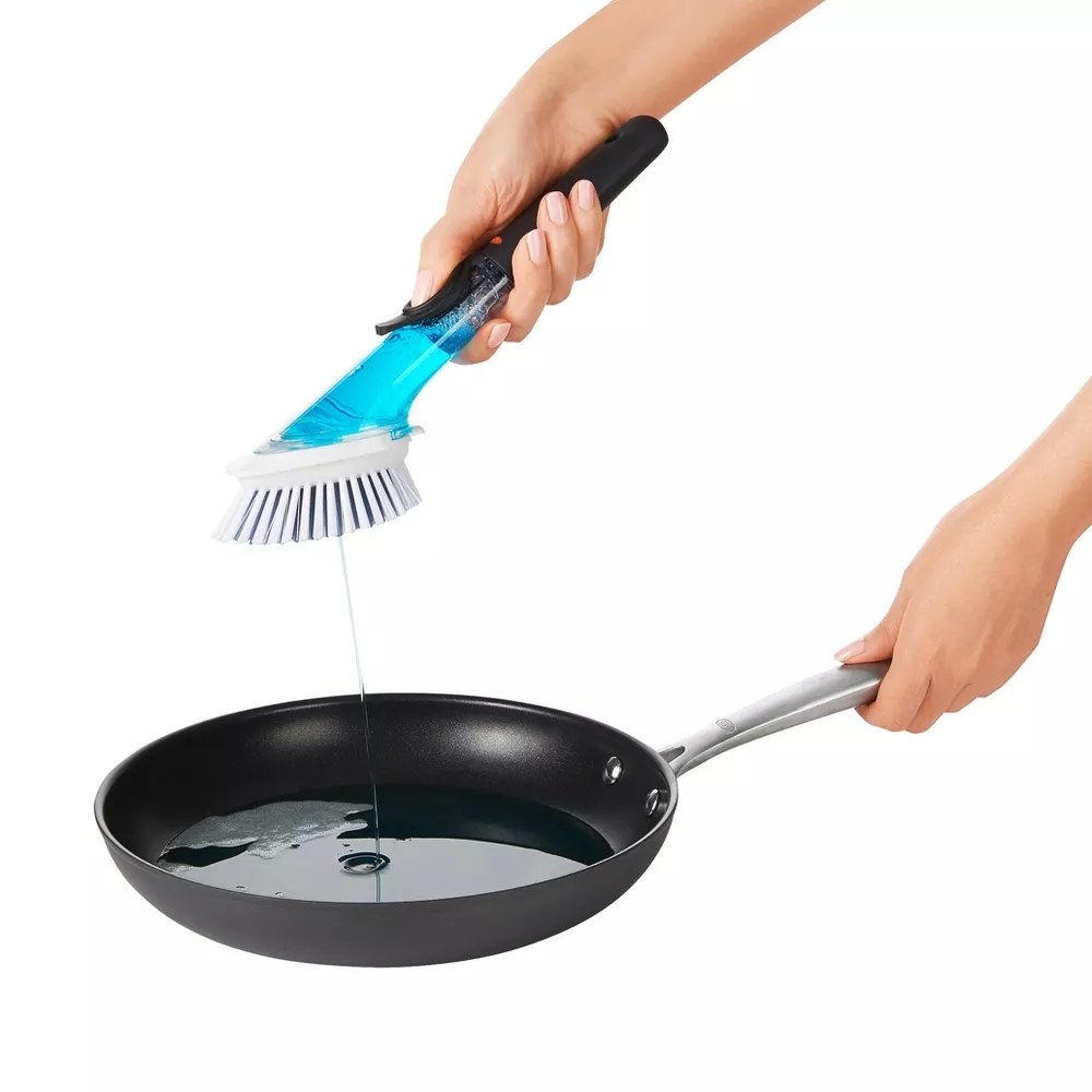 A model using the dish brush to dispense soap into a pan