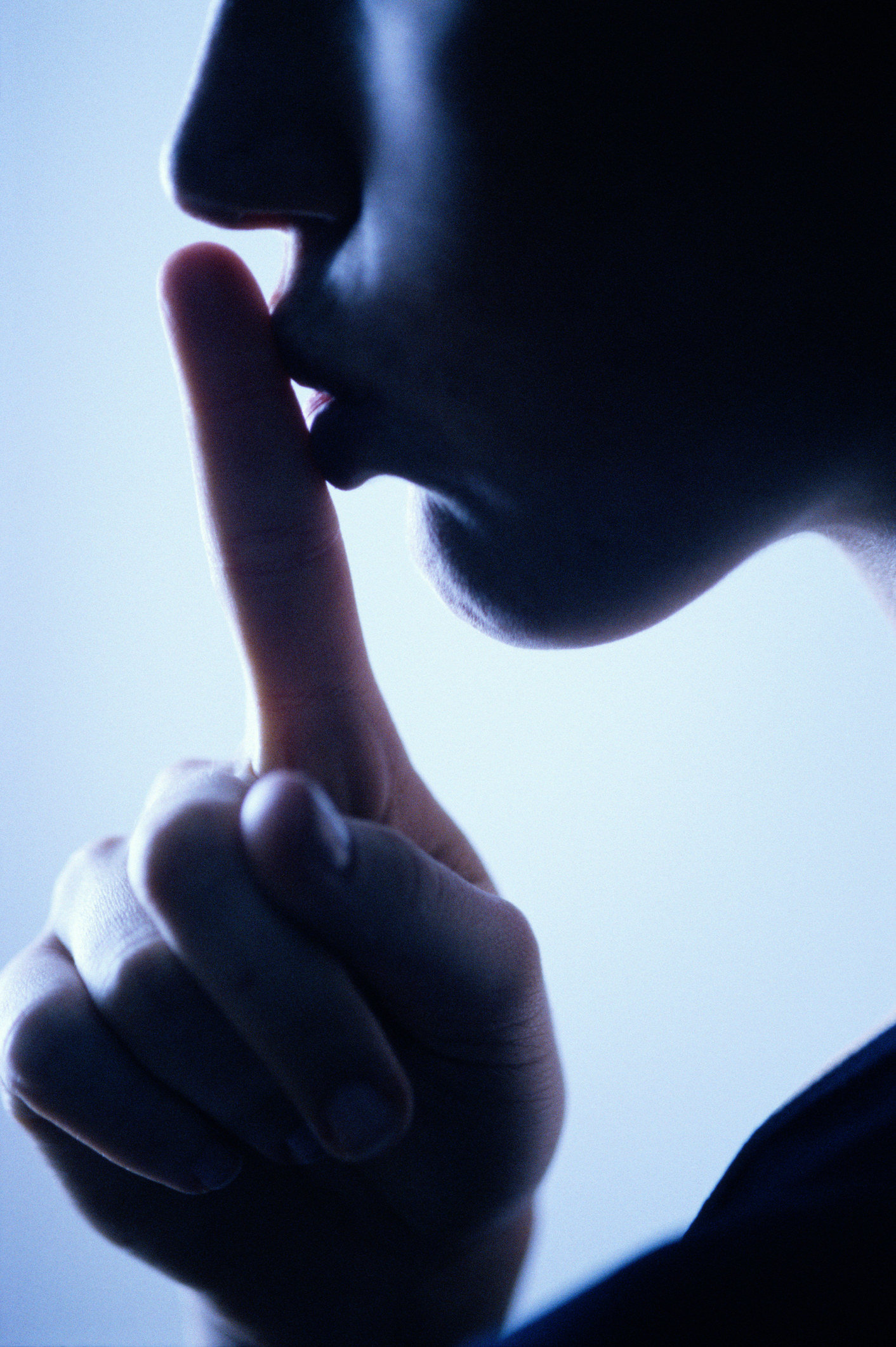 A person with a finger over their lips, shushing