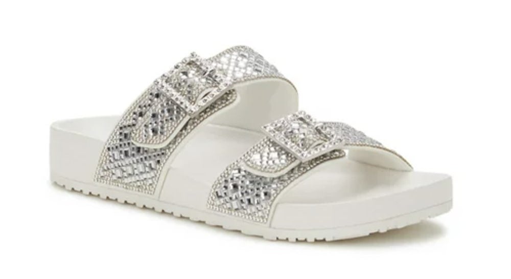 A pair of white slides with bedazzled straps