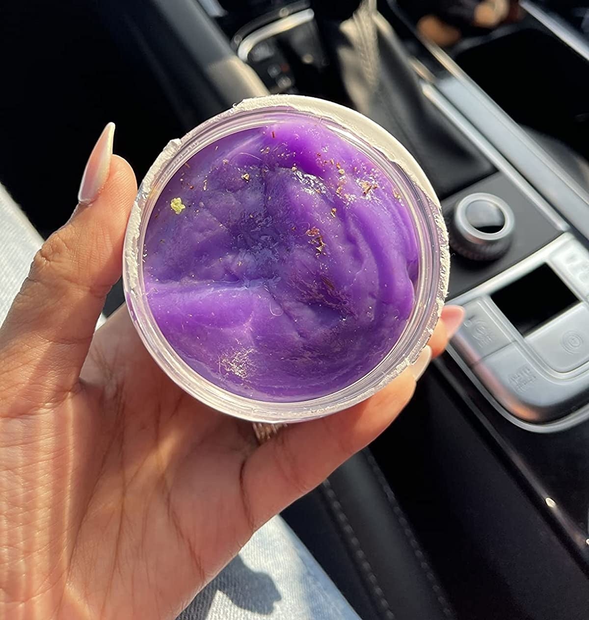 Reviewer holding a jar of purple car putty