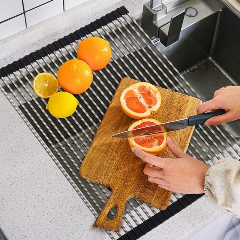 model slicing grapefruit on top of wood cutting board laying down on the silver roll-up dish drying rack