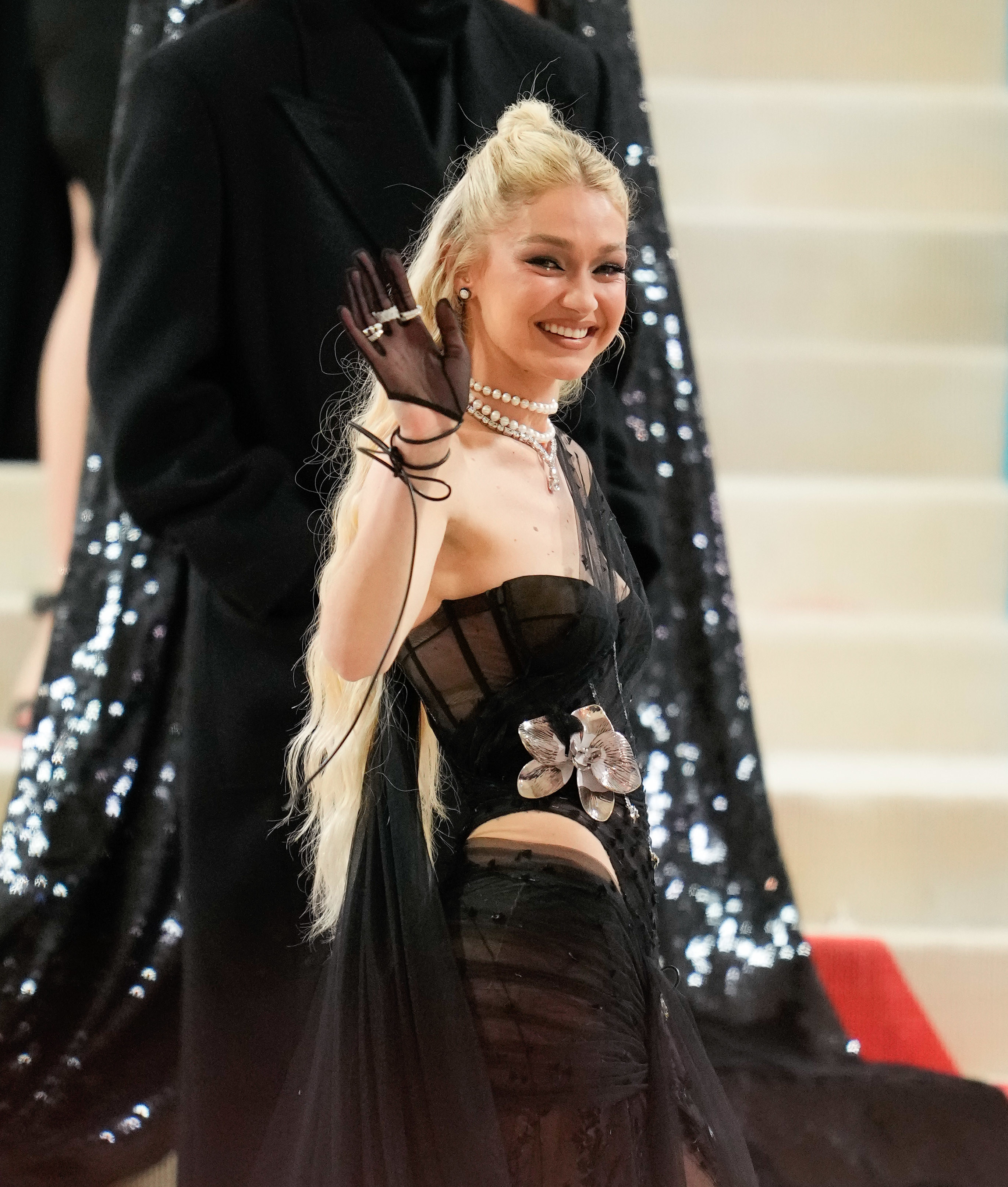 Gigi Hadid waves to the camera while walking up the steps at The Met Gala