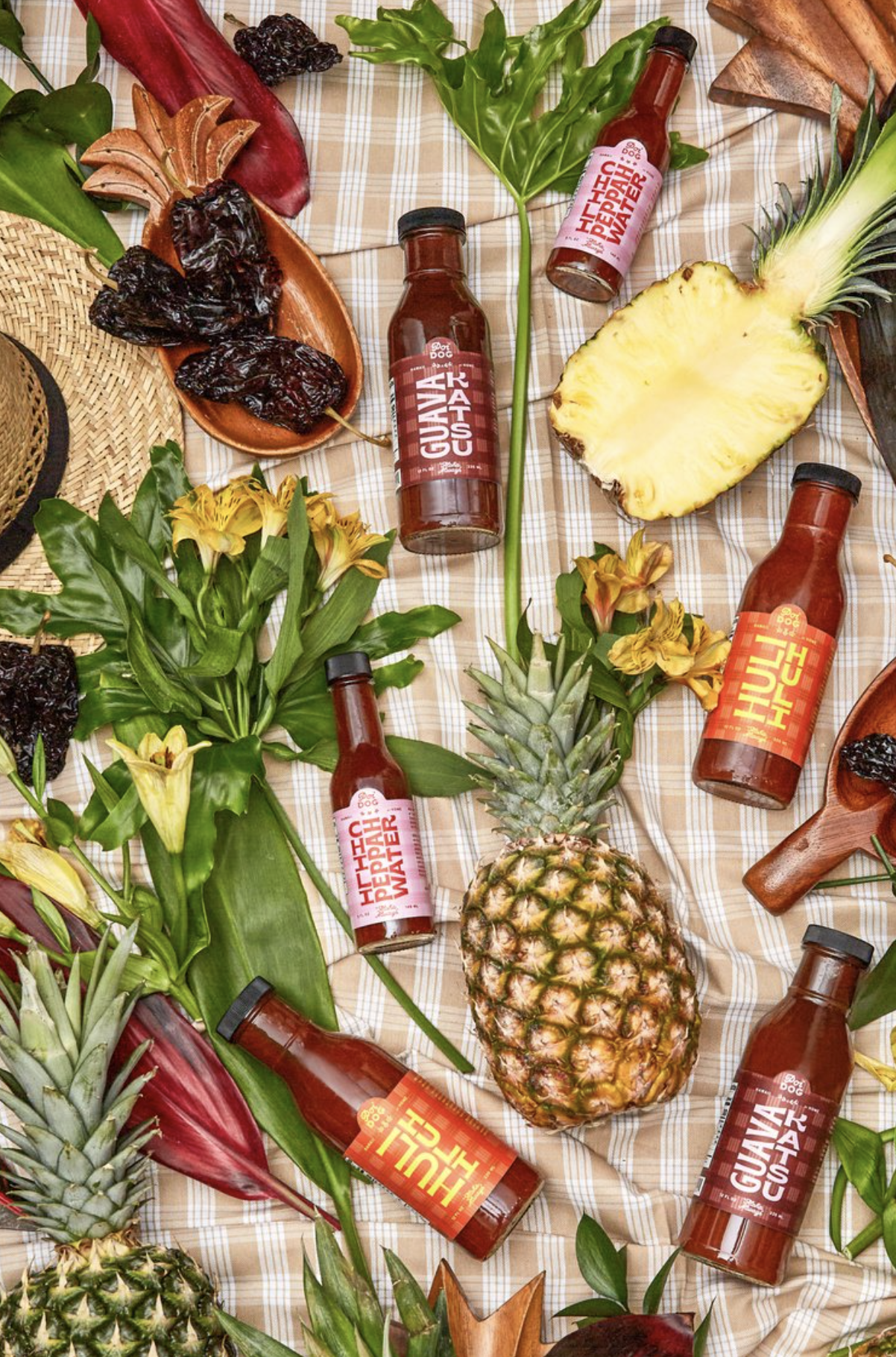 Poi Dog sauces surrounded by pineapples and Hawaiian plants.