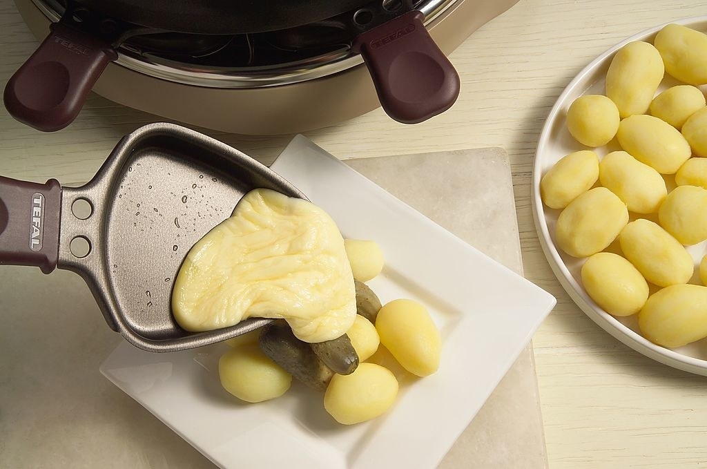 melted cheese being poured on small potatoes