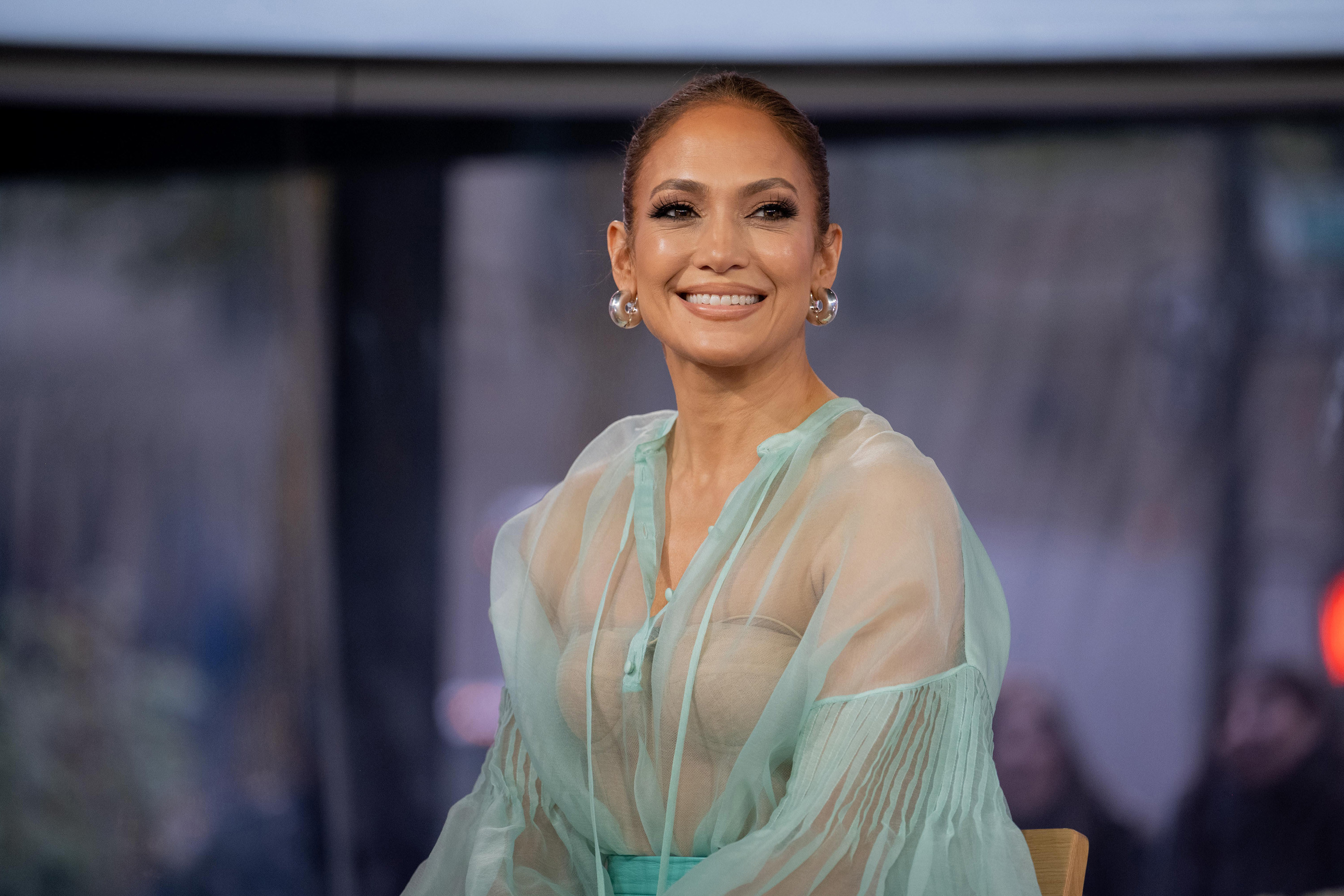 JLo smiling in a diaphanous outfit