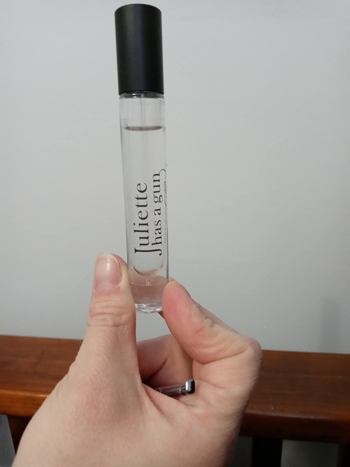 A reviewer holding a small bottle of perfume
