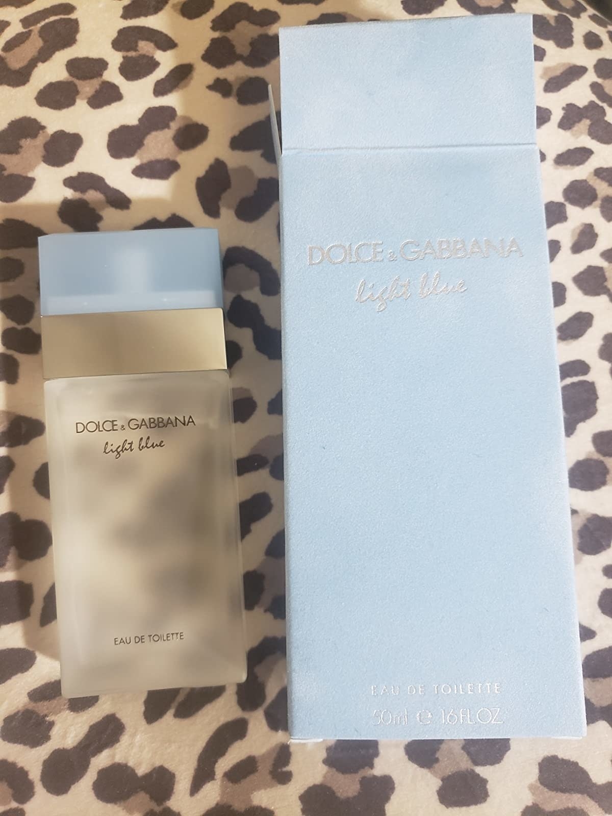 a reviewer&#x27;s photo of a white perfume bottle and the blue packaging it came in