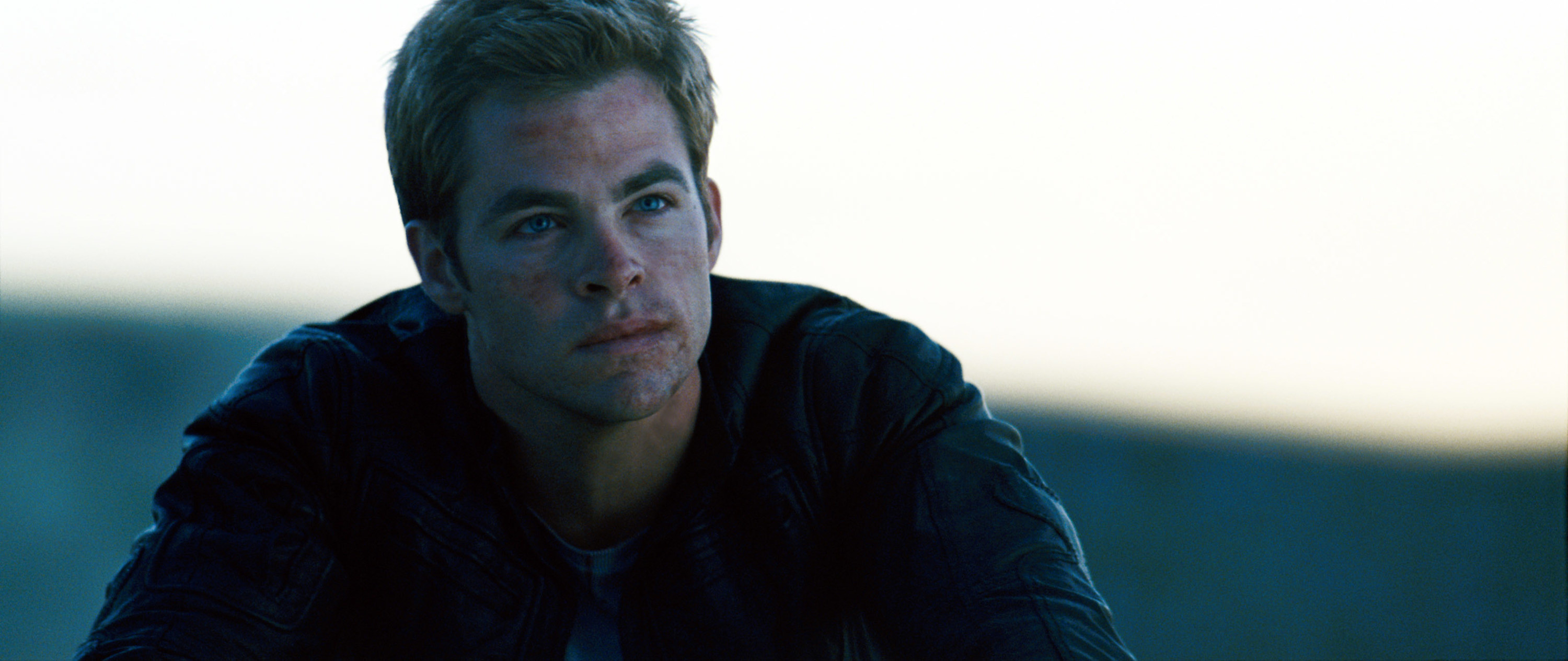 Chris Pine rides a motorcycle and looks up at the sky