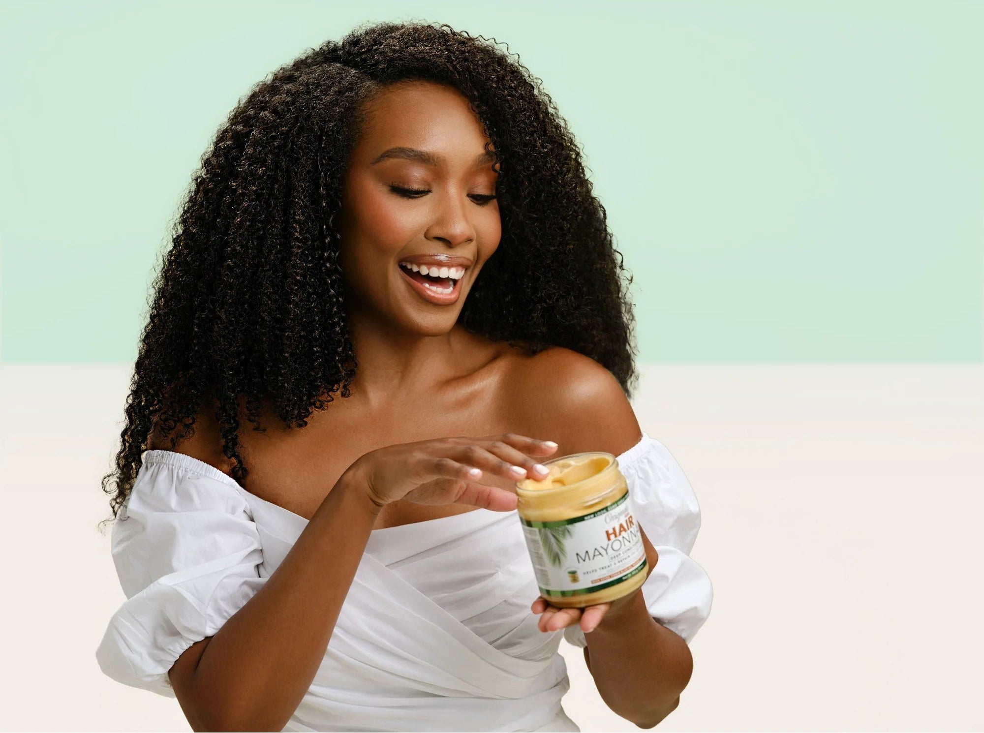 Model with curly hair holding the mask