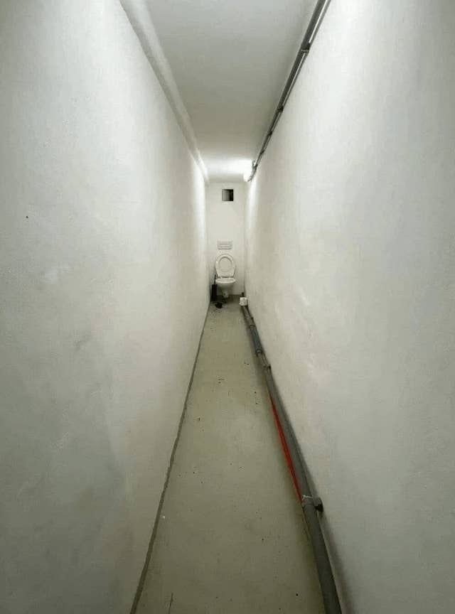 A long hallway with a toilet at the end