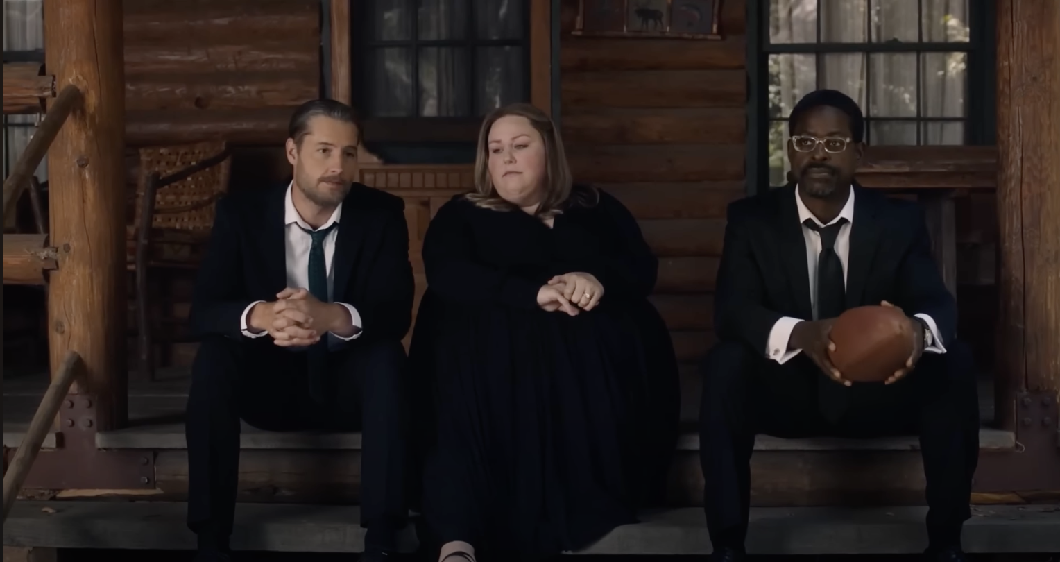 Kevin, Kate, and Randall sit on the steps of a cabin