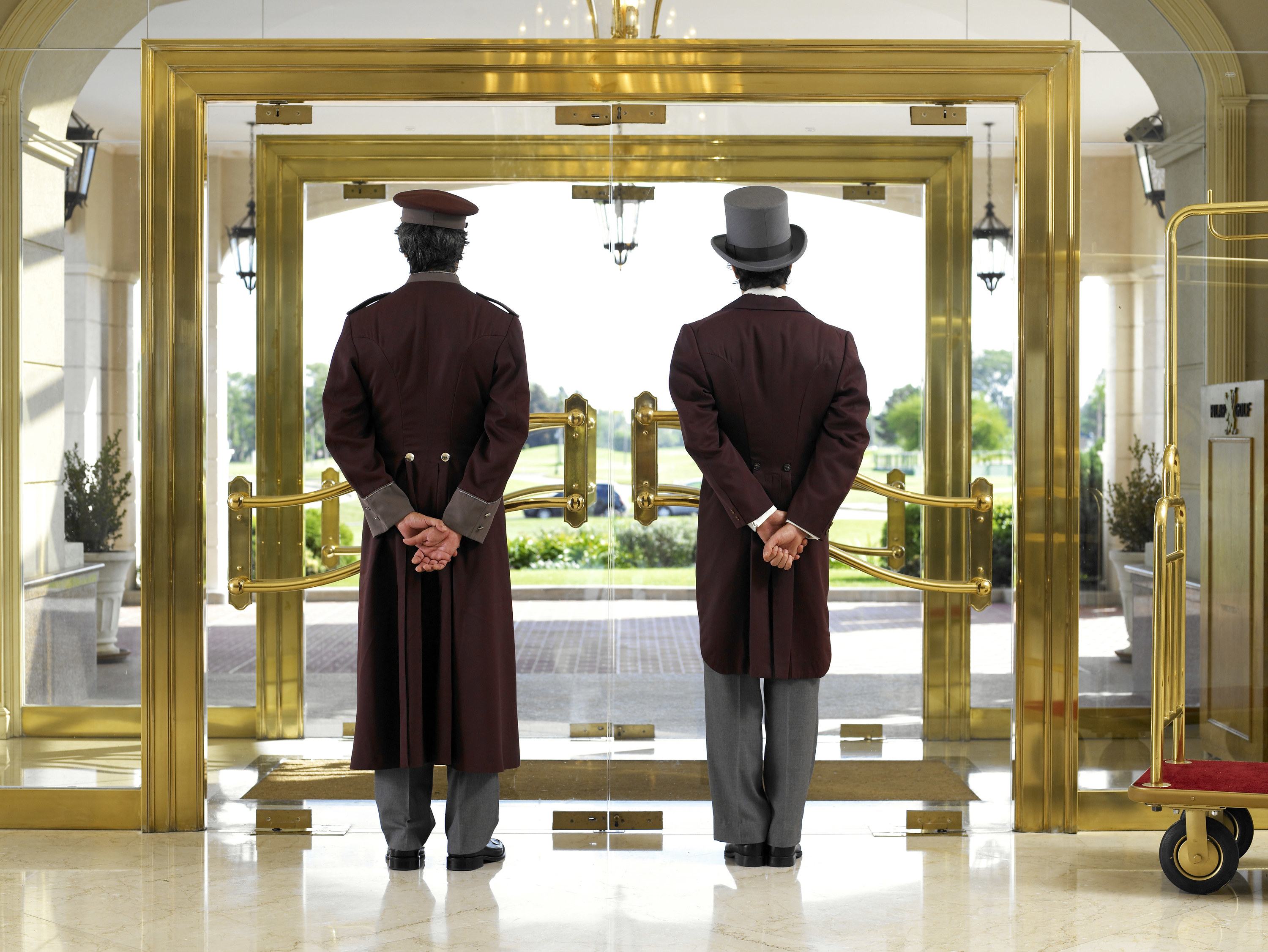 Two hotel workers facing the front door of the hotel