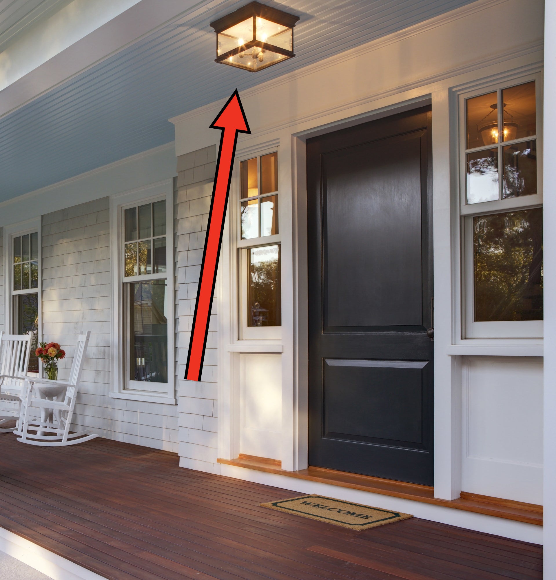 arrow pointing to lightbulbs in an outdoor light casing on a front porch