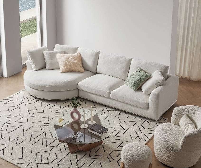 A white-ish sectional with a round chaise is shown in a living room