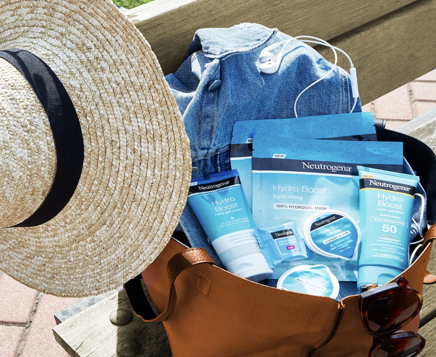A beach hat and bag with face mask, sunscreen, and a jean jacket
