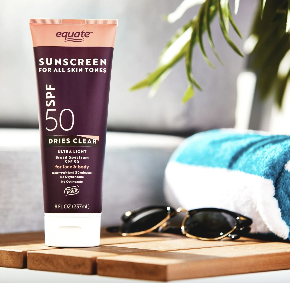 A rube of sunscreen lotion, sunglasses and a beach towel