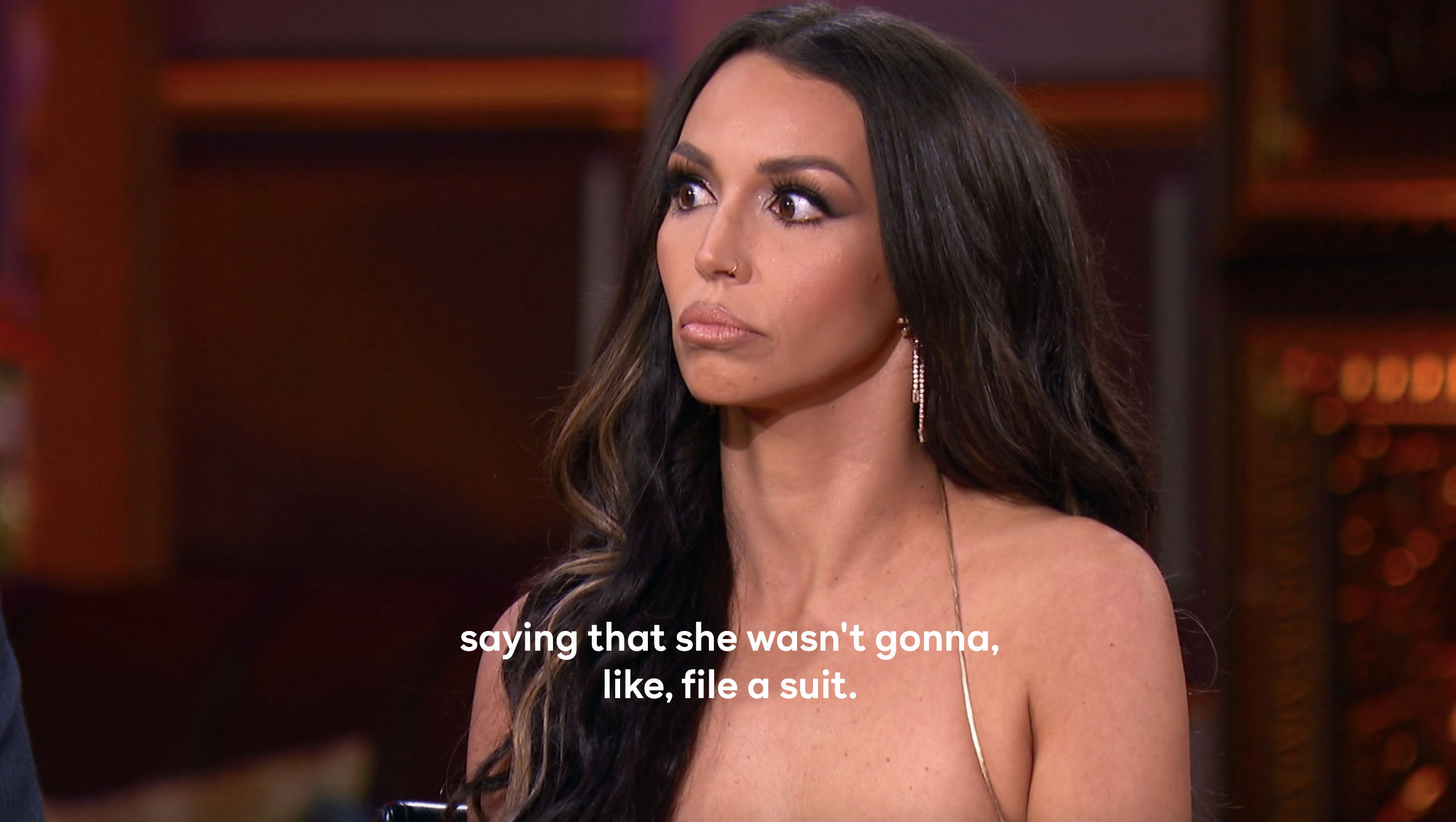 Scheana with her eyes wide on stage while Tom Sandoval speaks