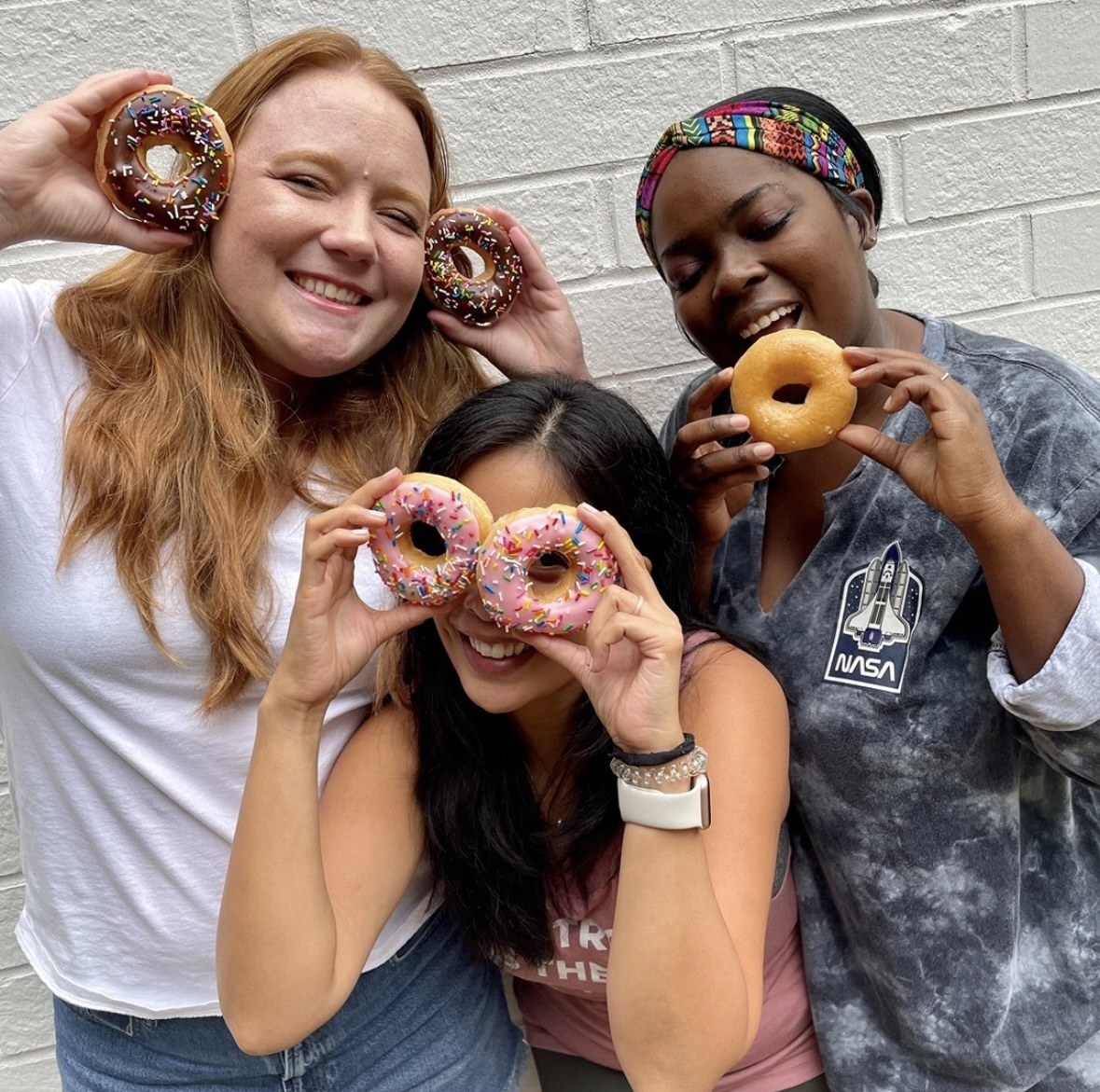 three people posing with donuts