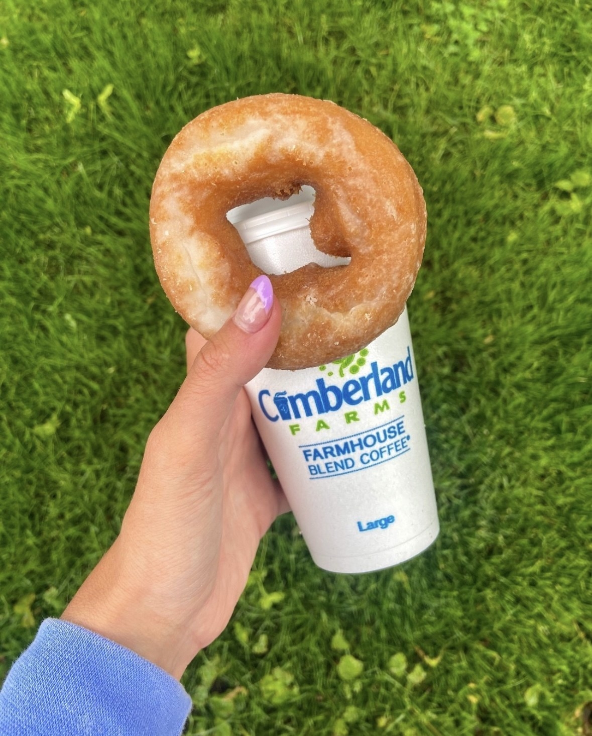 a hand holding a coffee and donut