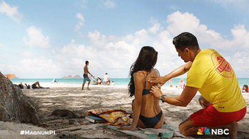Person applying sunscreen to someone on the beach