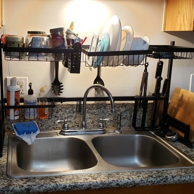 Black over-the-counter organizer over sink with dishes and cups on it