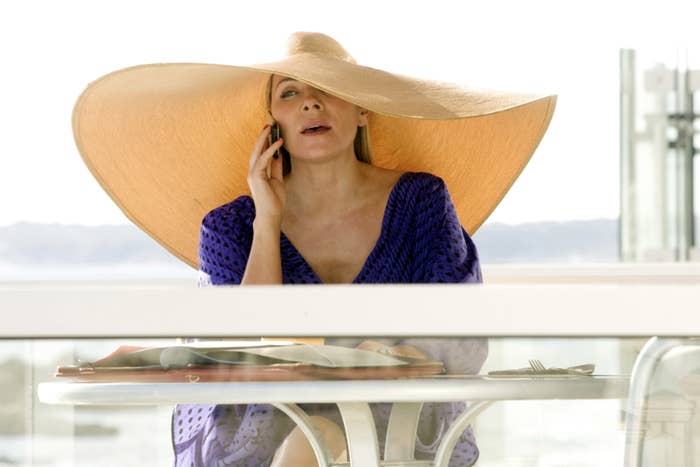 萨曼莎坐在阳台表和讲电话时戴着超大号的遮阳帽