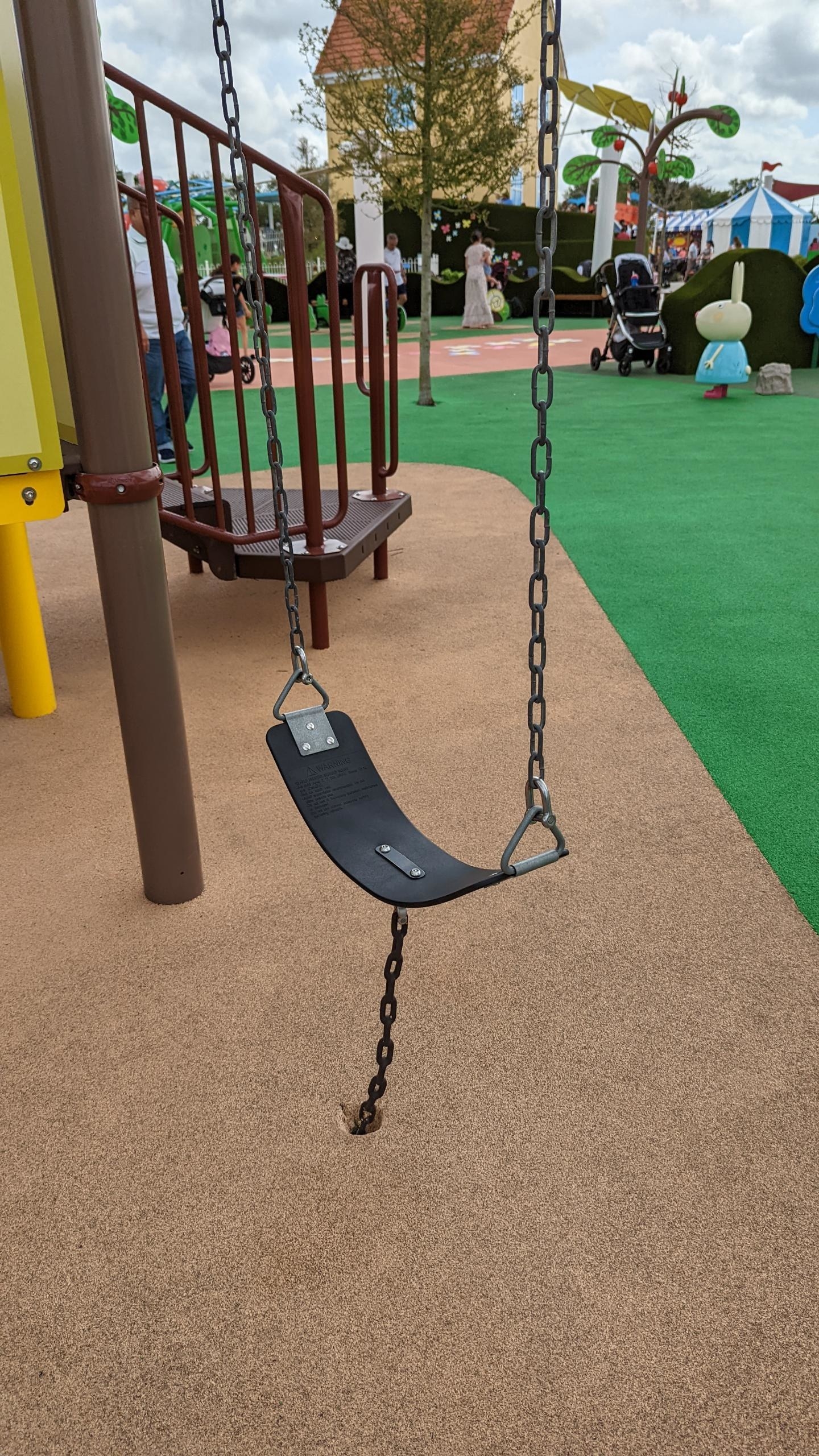 A swing with a chain that extends into the ground