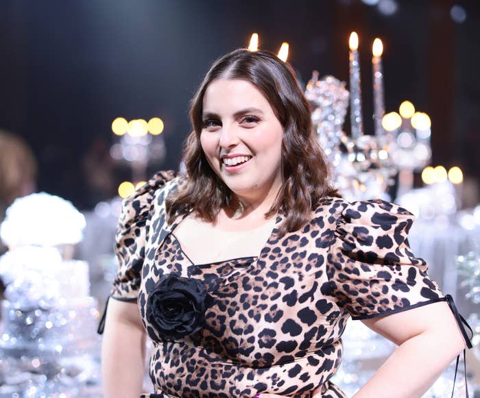 Beanie smiles as she stands in front of an ornate table wearing a leopard print outfit