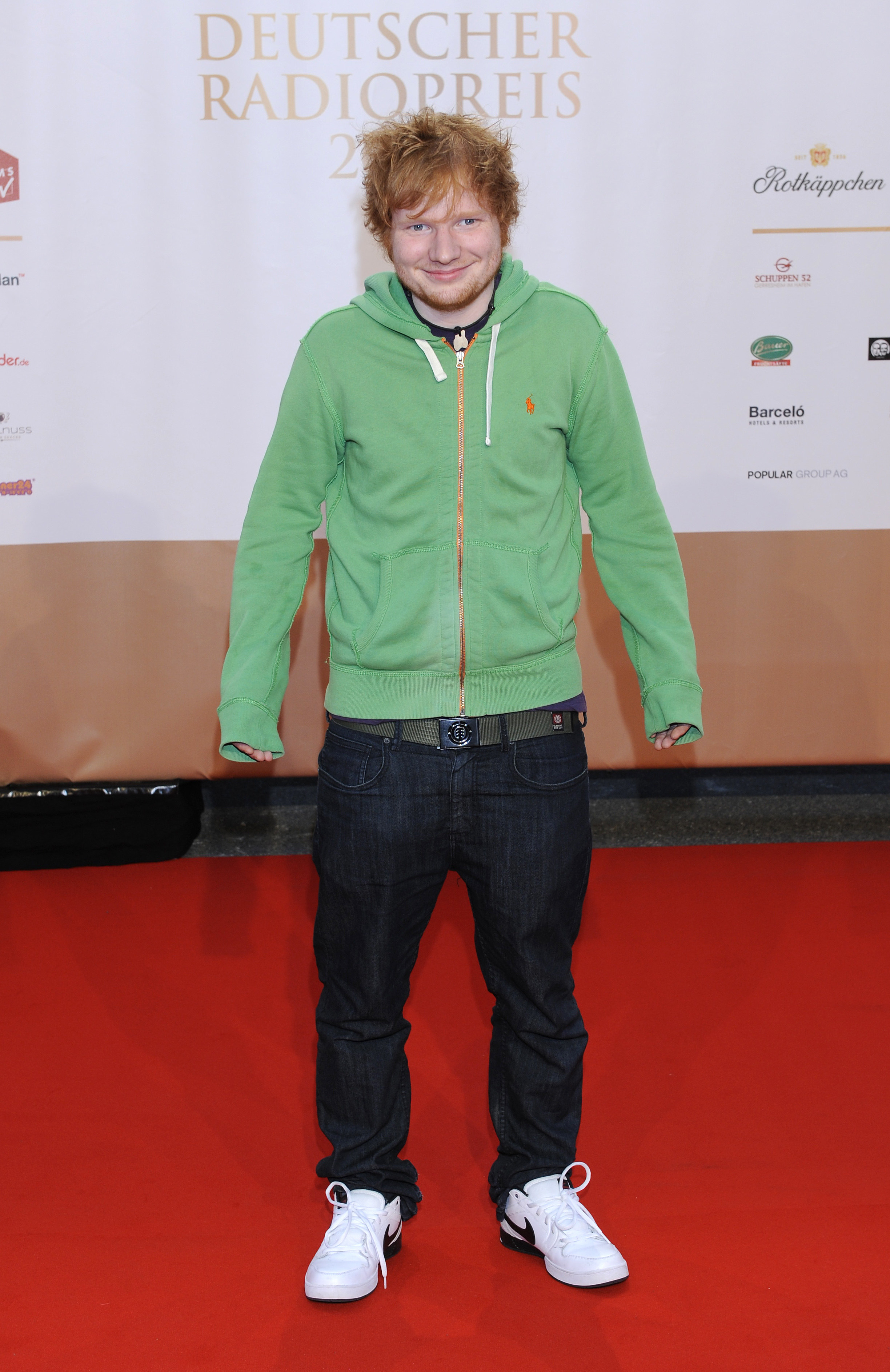 He&#x27;s smiling, and the hoodie sleeves are extending past his hands