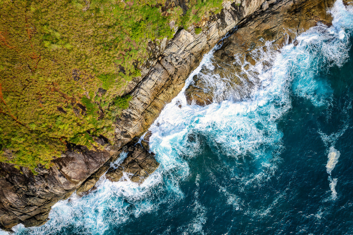 sea wave crashing on rock coast with spray and foam