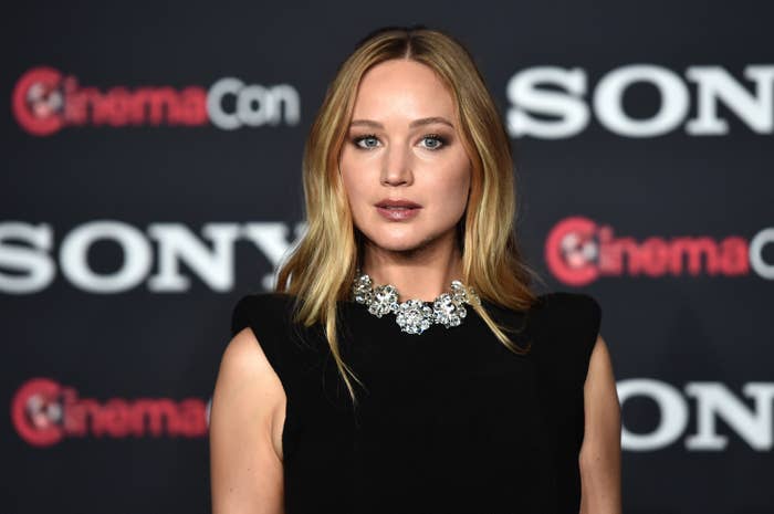 Close-up of JLaw in a sleeveless outfit and thick bejeweled choker necklace