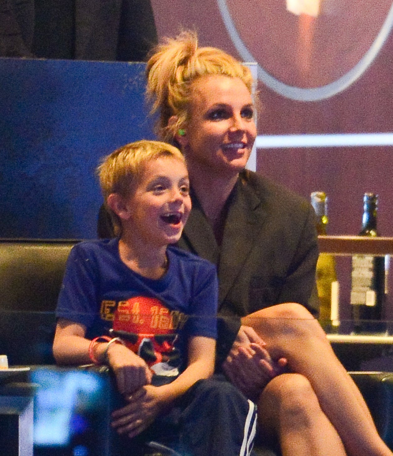 Britney and one of her young sons. smiling as they sit next to each other at an event