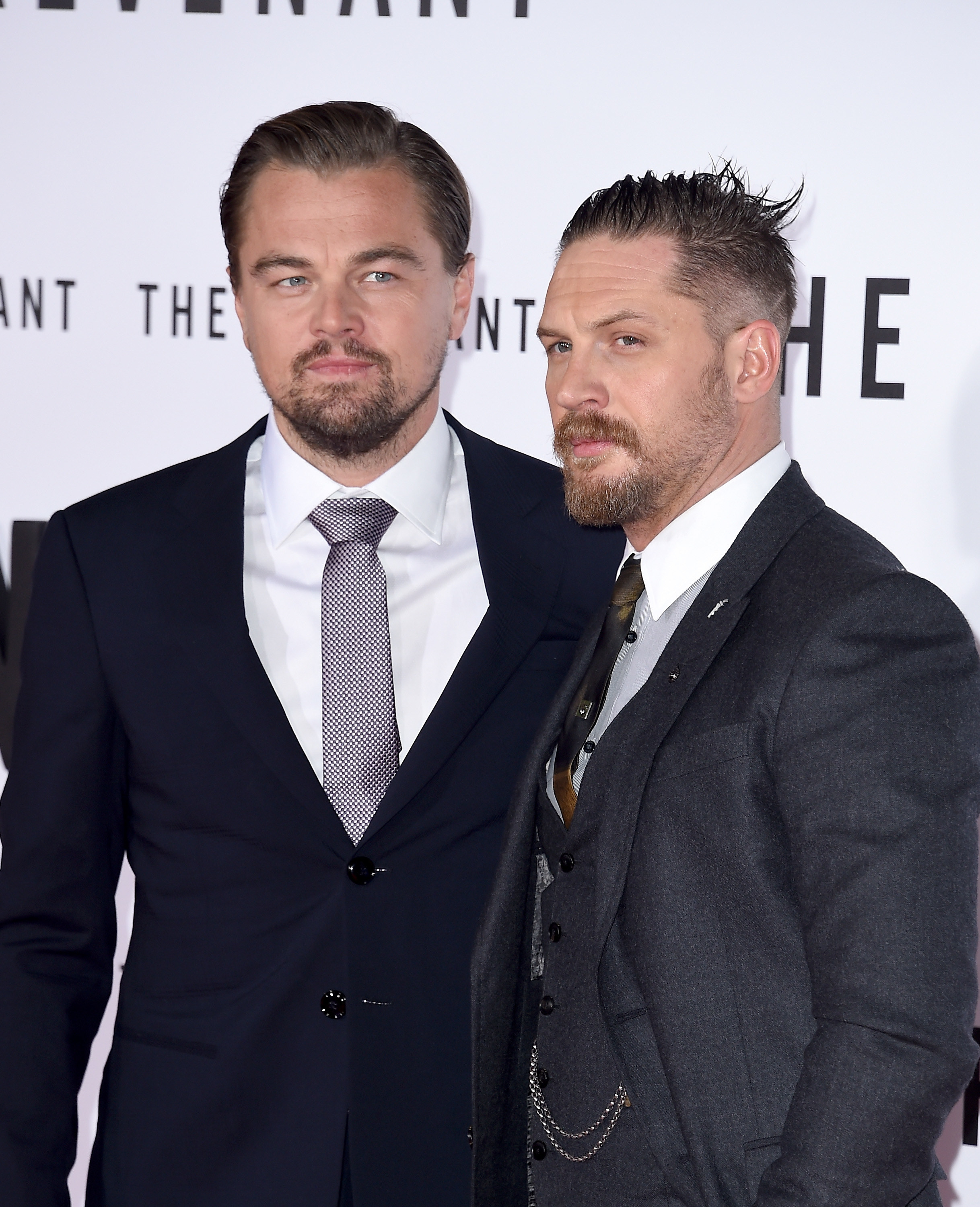 Leo DiCaprio and Tom Hardy standing together in suits and ties