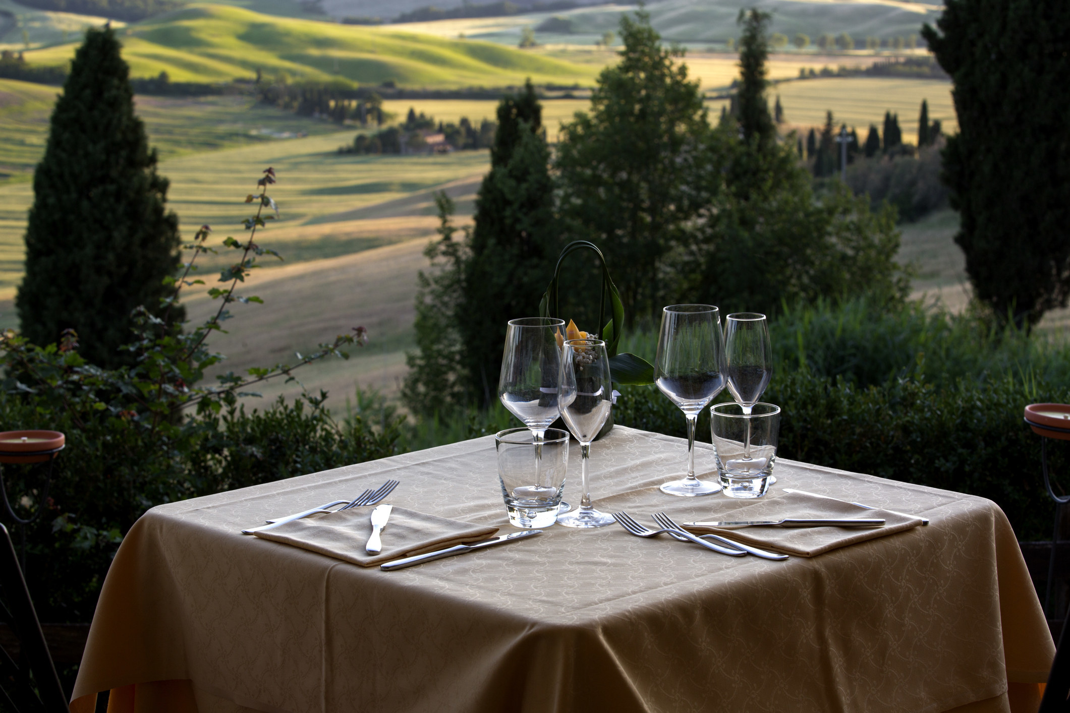 Table set with glasses and utensils with a view of the beautiful landscapes of Val d&#x27;Orcia valley in Tuscany