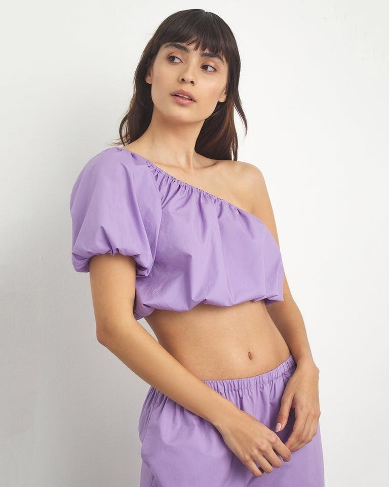 Model wearing purple one-shoulder top with matching bottoms